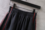 Black Balenciaga shorts close-up of elastic waistband and pleats with red trim.