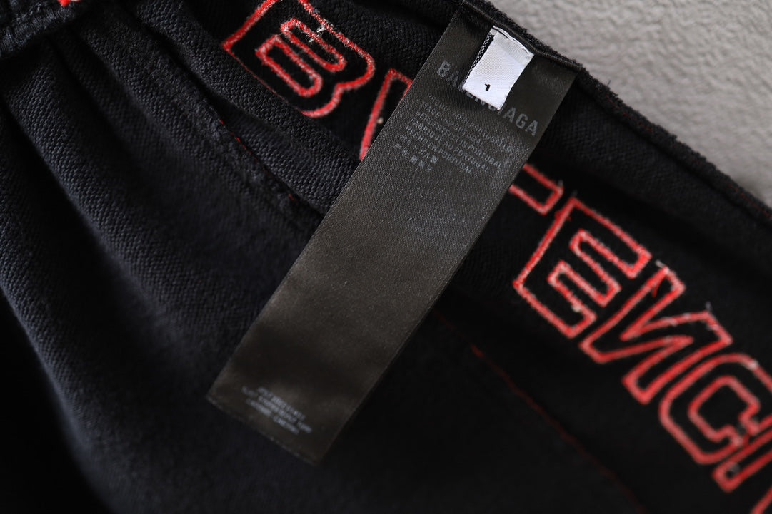 Black fabric shorts with Balenciaga label tag and red embroidered side lettering.