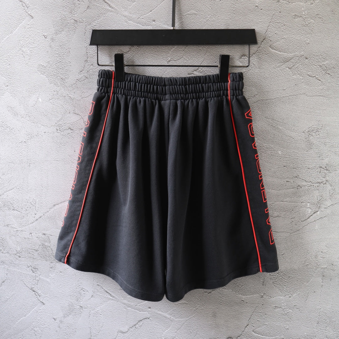 Black Balenciaga shorts with red-trimmed sides and pleated front, elastic waist.