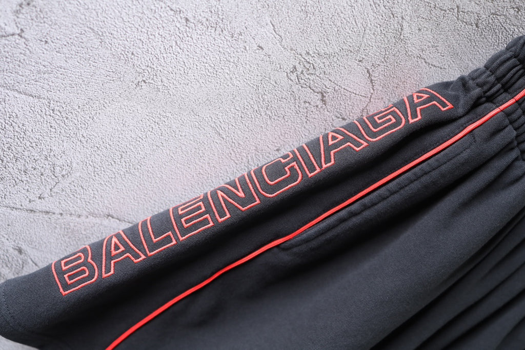 Black Balenciaga shorts with embroidered red logo text on side seam and contrast trim.