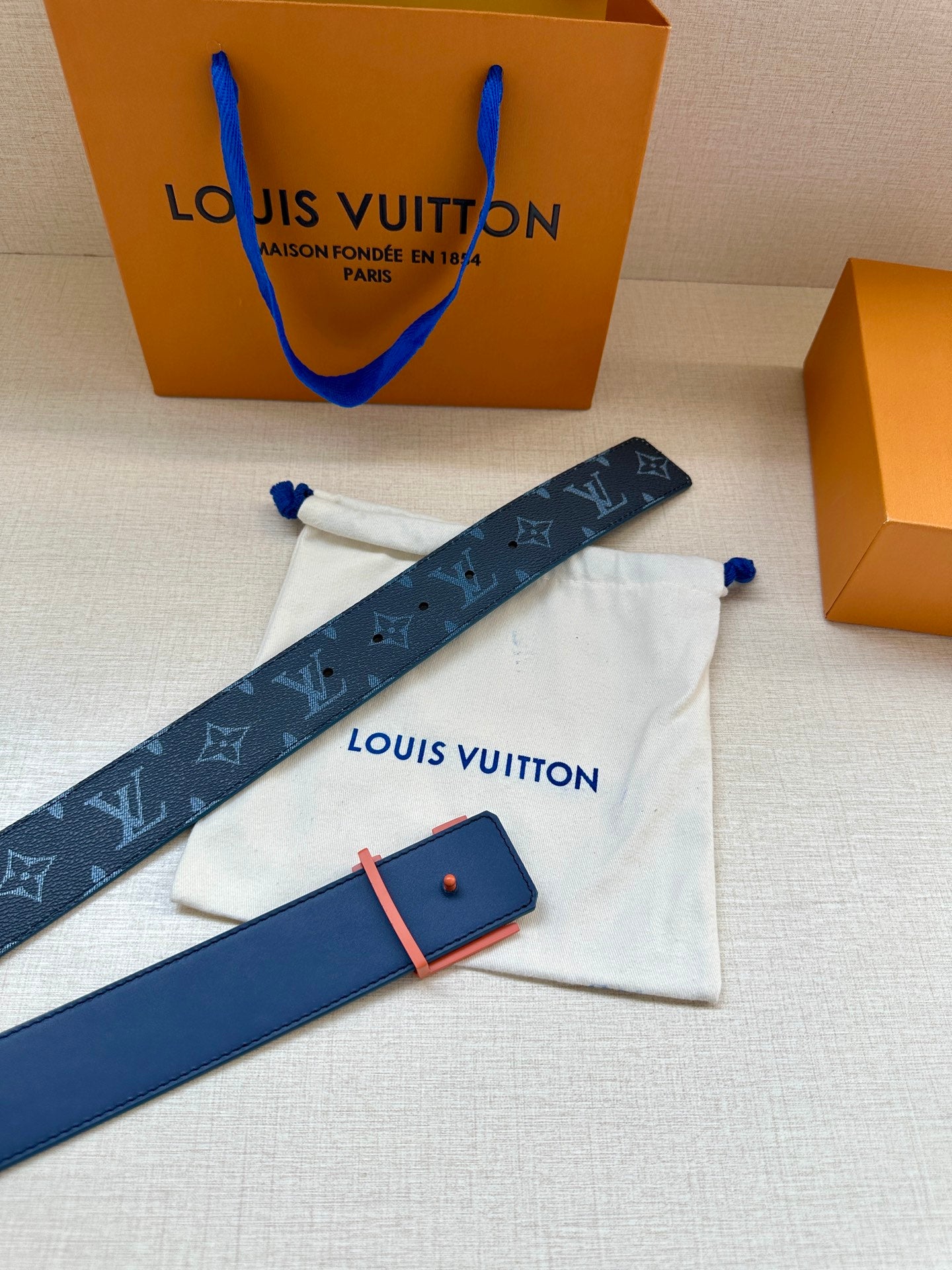 Louis Vuitton belt with dark blue monogram strap, orange buckle and case