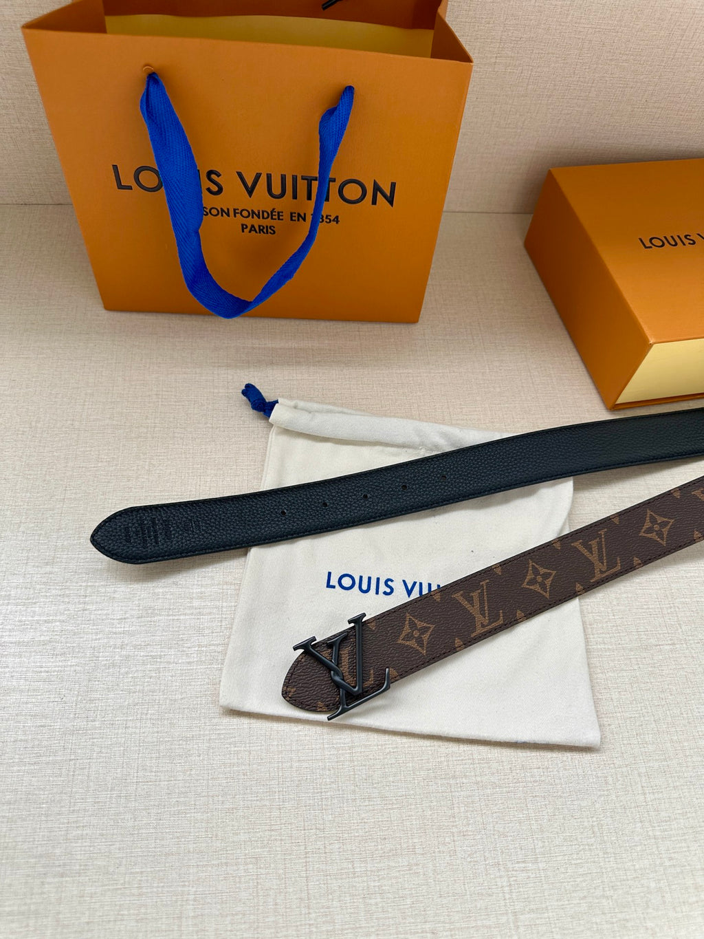 Louis Vuitton monogram belt with dark leather strap, metal V buckle, and strap end