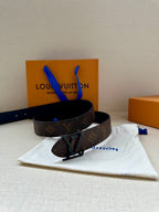 Louis Vuitton monogram belt with dark leather strap and metal V buckle, angled view