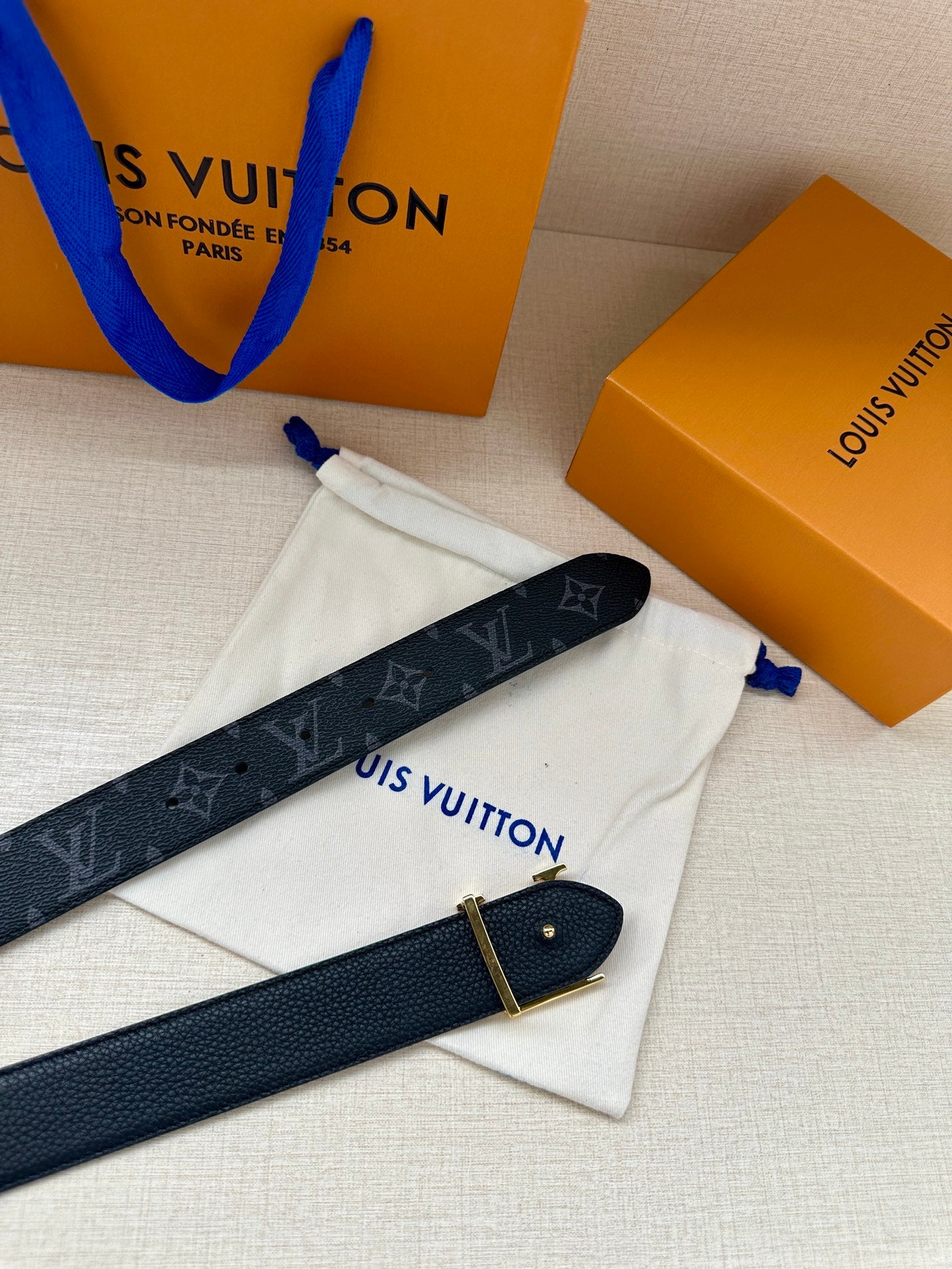 Louis Vuitton monogram belt with gold-tone buckle, dark navy with repeating LV logos.
