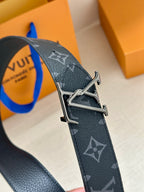Louis Vuitton monogram belt close-up with silver-tone buckle and dark navy pattern.