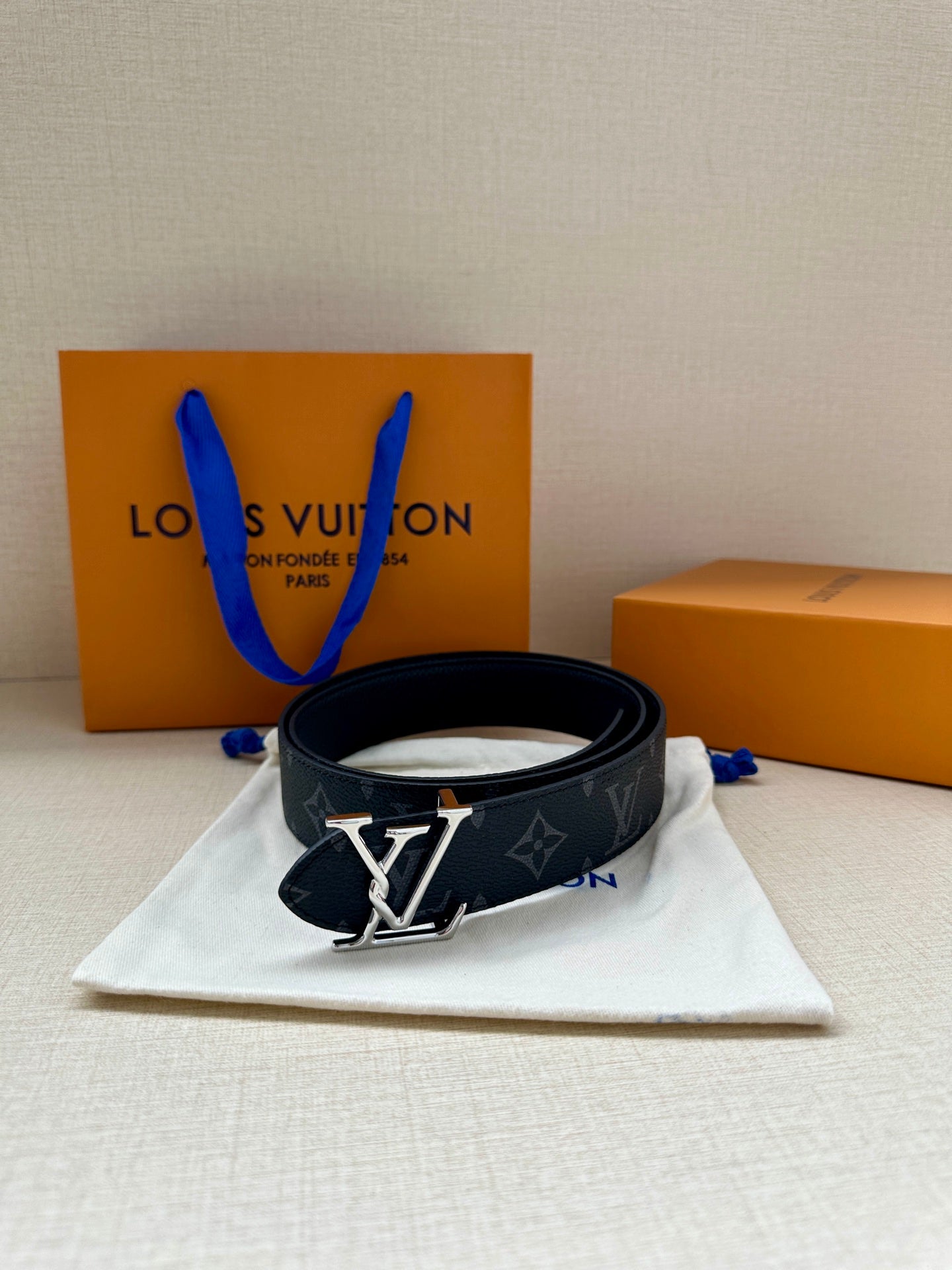 Louis Vuitton monogram belt with gold-tone LV buckle, dark navy repeating pattern.