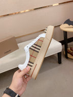 Low-top sneakers showing side profile with white upper and beige plaid stripe