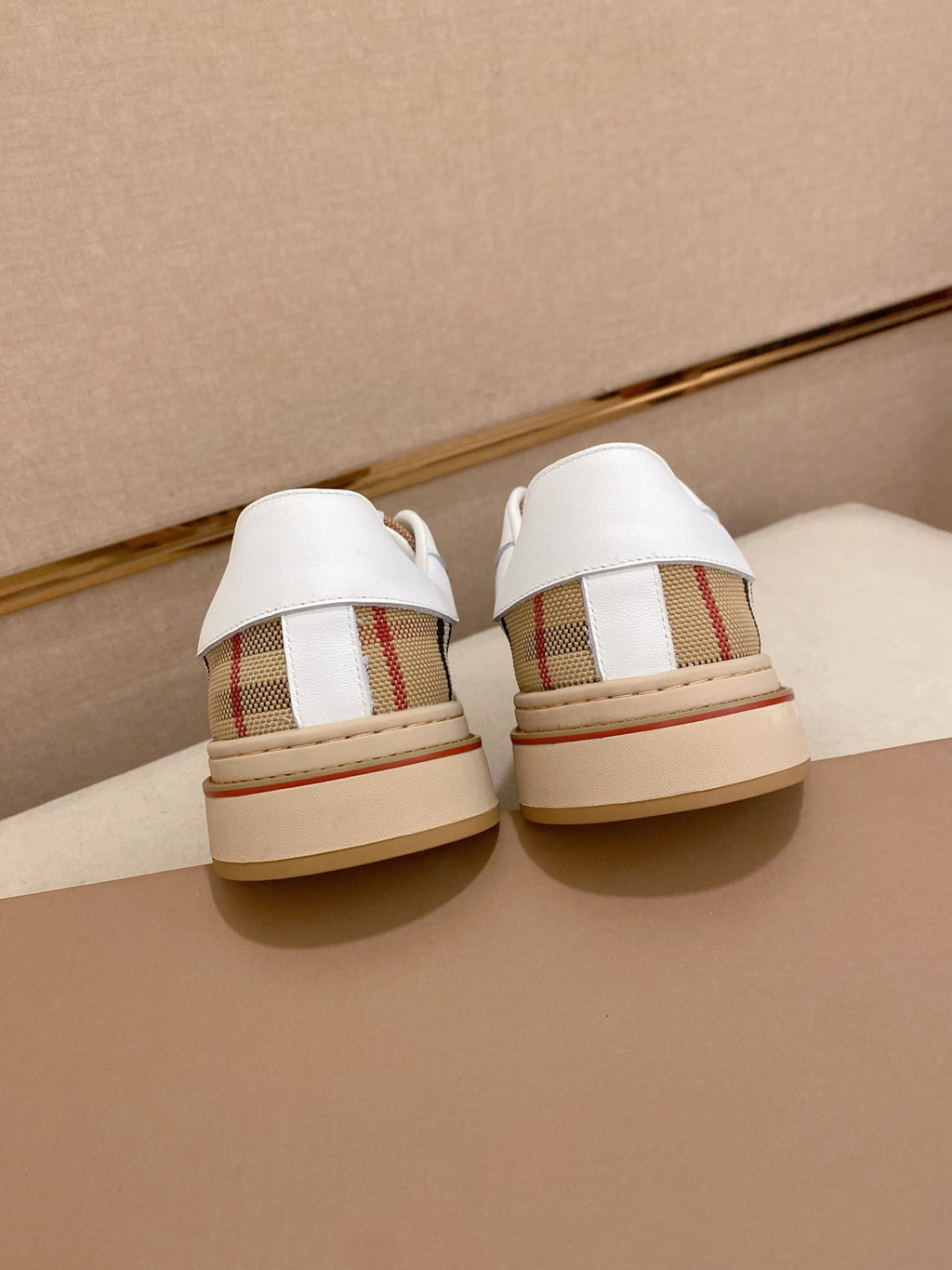 Back view of white low-top sneakers with plaid heel panels and cream soles