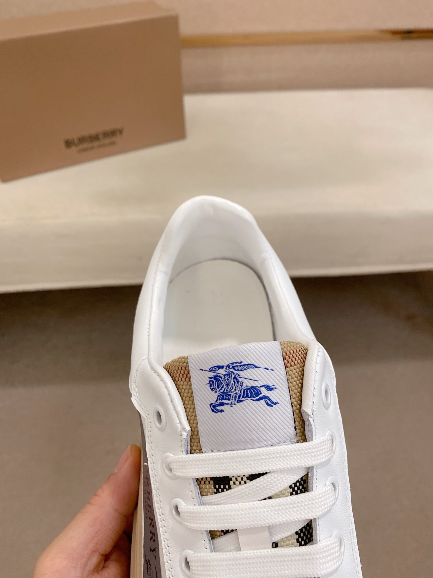 White sneaker with blue logo embroidery on tongue and white lace-up closure