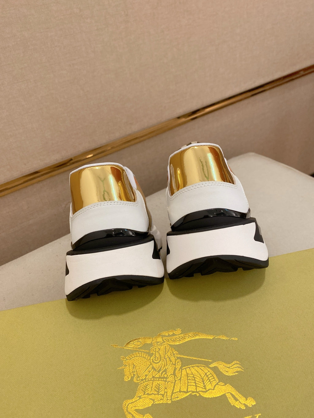 Burberry sneakers back view, white leather with gold heel tabs and black cushioned sole