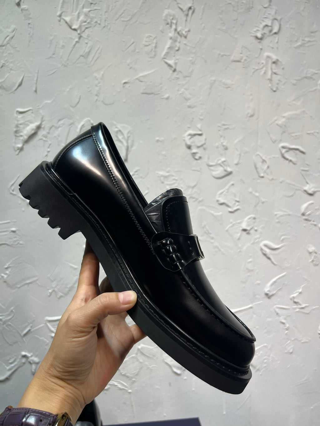 Black leather loafer with square buckle strap and ridged platform sole, angled view