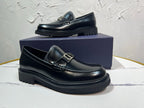 Black leather loafer with square buckle strap and chunky treaded sole, side view