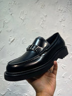 Black leather loafer with square buckle strap and glossy finish, side close-up