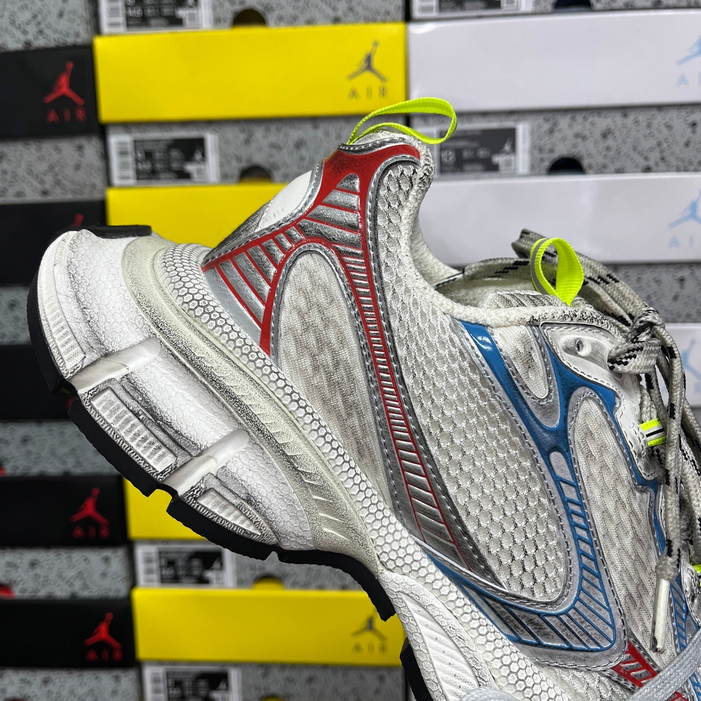 Chunky running shoe side view: white mesh, red border stripe, blue panel, neon green laces.