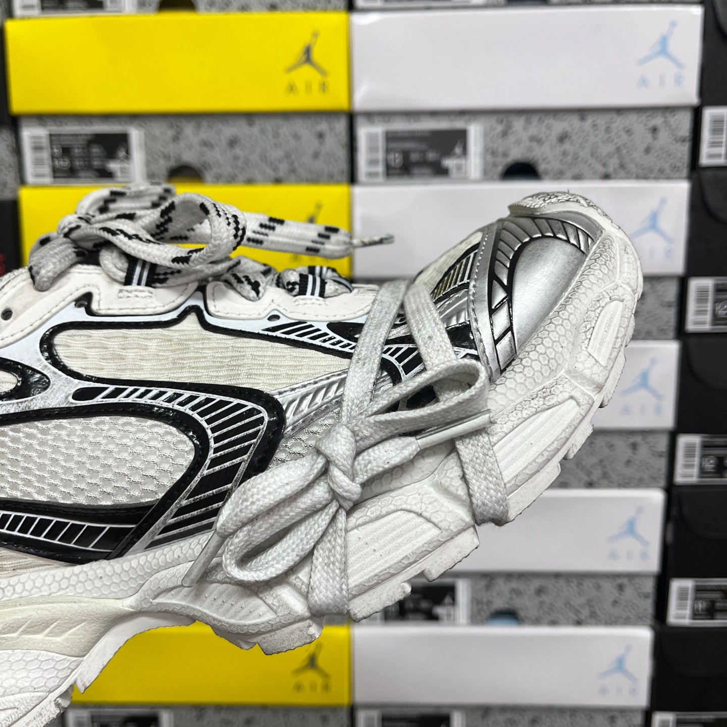 White Balenciaga sneakers, side view with black piping accents and lace-up front.