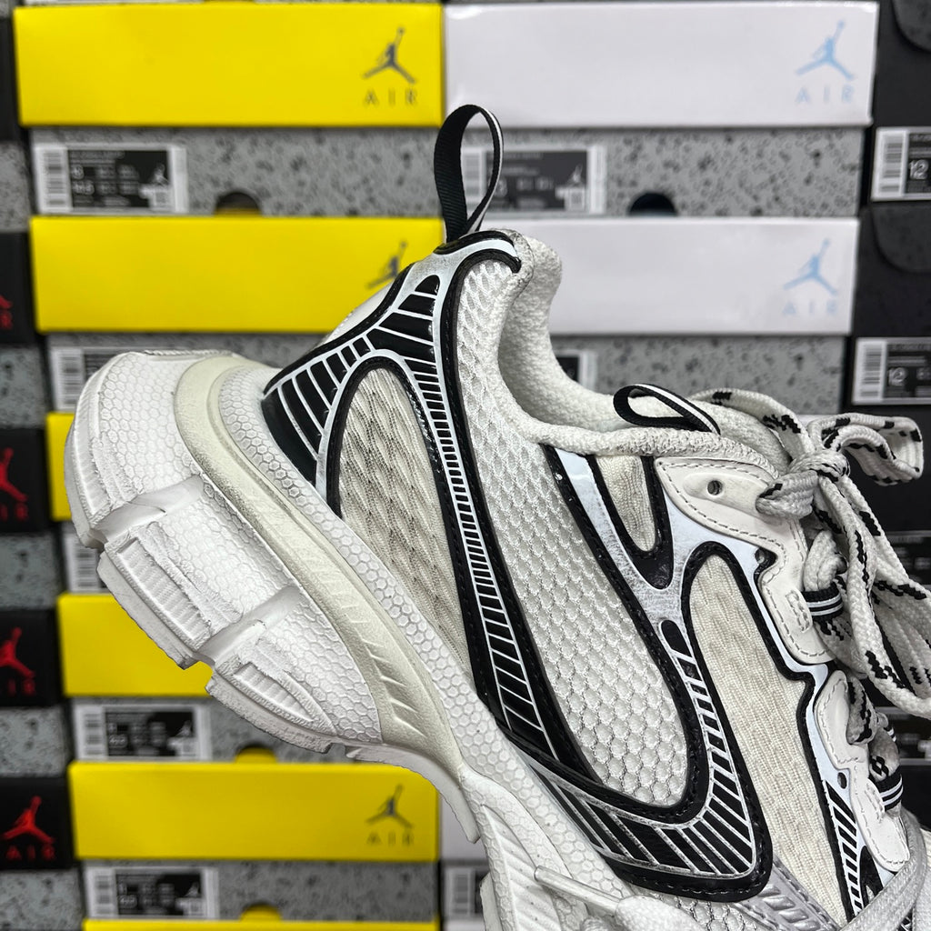 White Balenciaga sneakers with black side stripe trim, lace-up closure, padded collar.