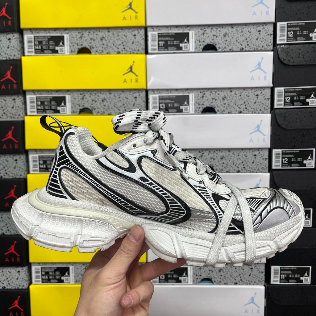 White Balenciaga sneakers side view with black accents, lace-up front and chunky sole.
