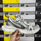 White Balenciaga sneakers side view with black accents, lace-up front and chunky sole.