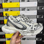 White Balenciaga sneakers with black trim, mesh panels, lace-up front, chunky sole.