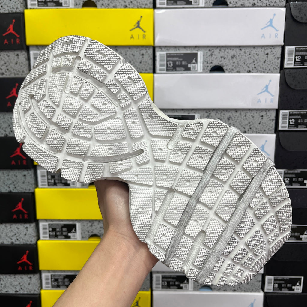 White Balenciaga sneakers outsole with textured traction pattern, shoe held at underside.
