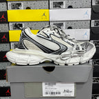 White lace-up Balenciaga sneakers with black accents and textured panels, chunky outsole.