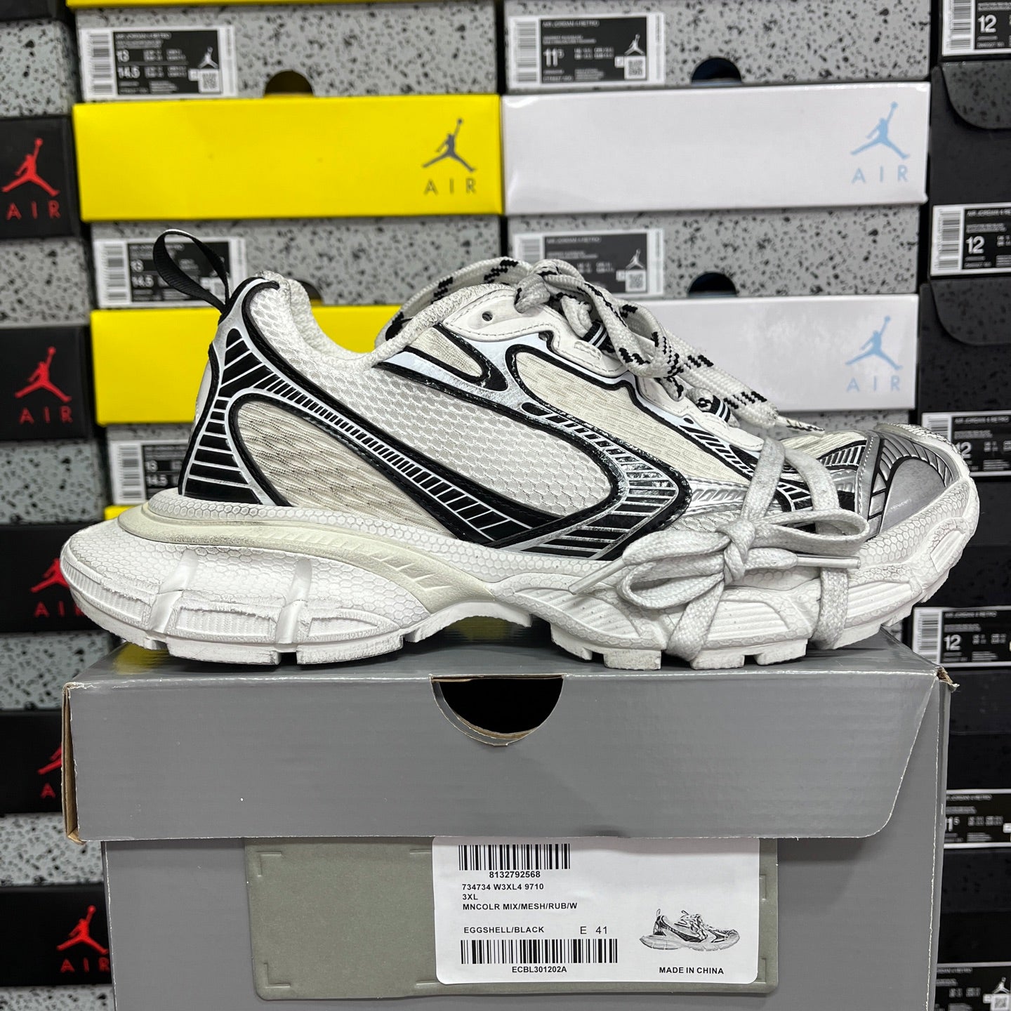White lace-up Balenciaga sneakers with black accents and textured panels, chunky outsole.