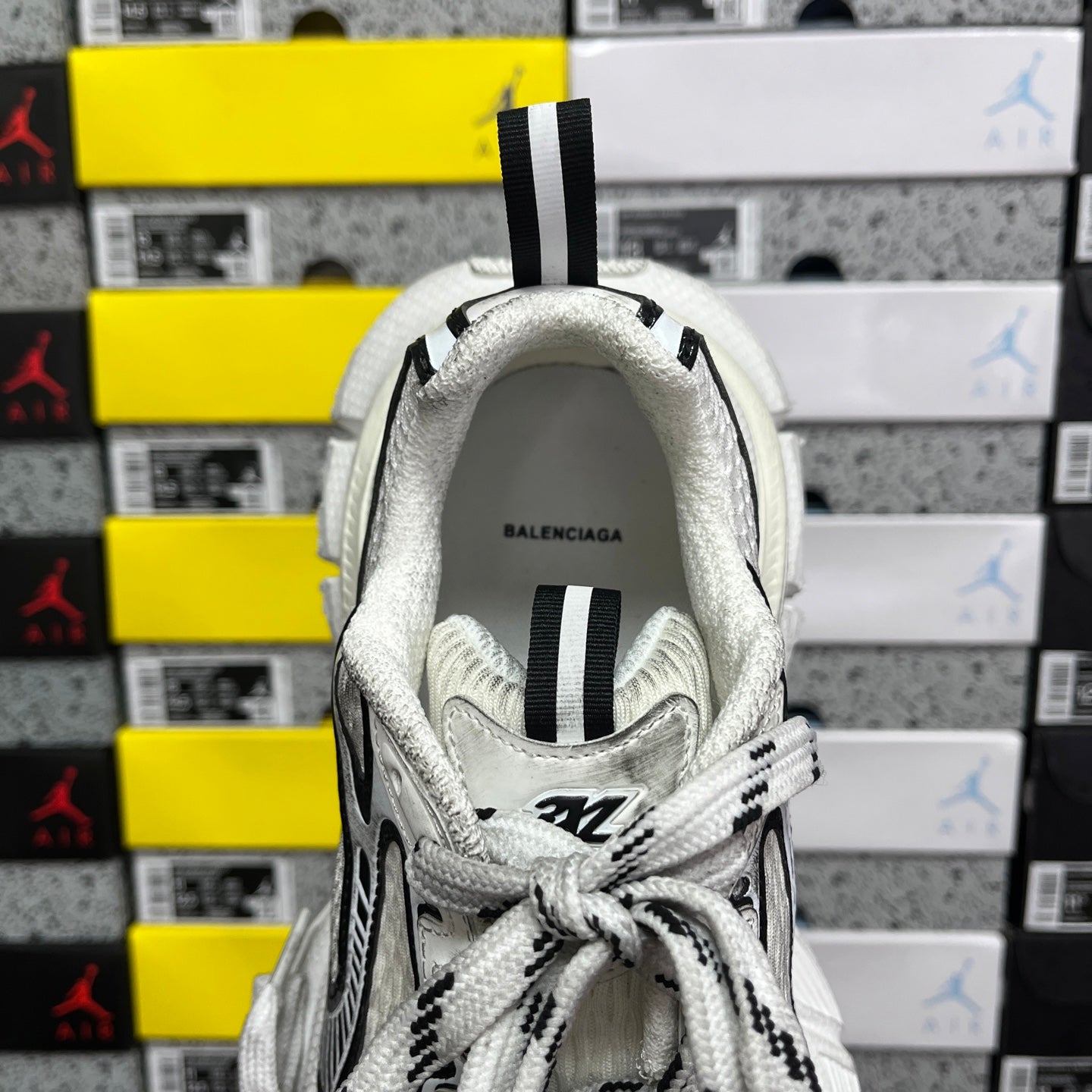 White Balenciaga sneaker tongue with black-and-white stripe label and lace-up top view.