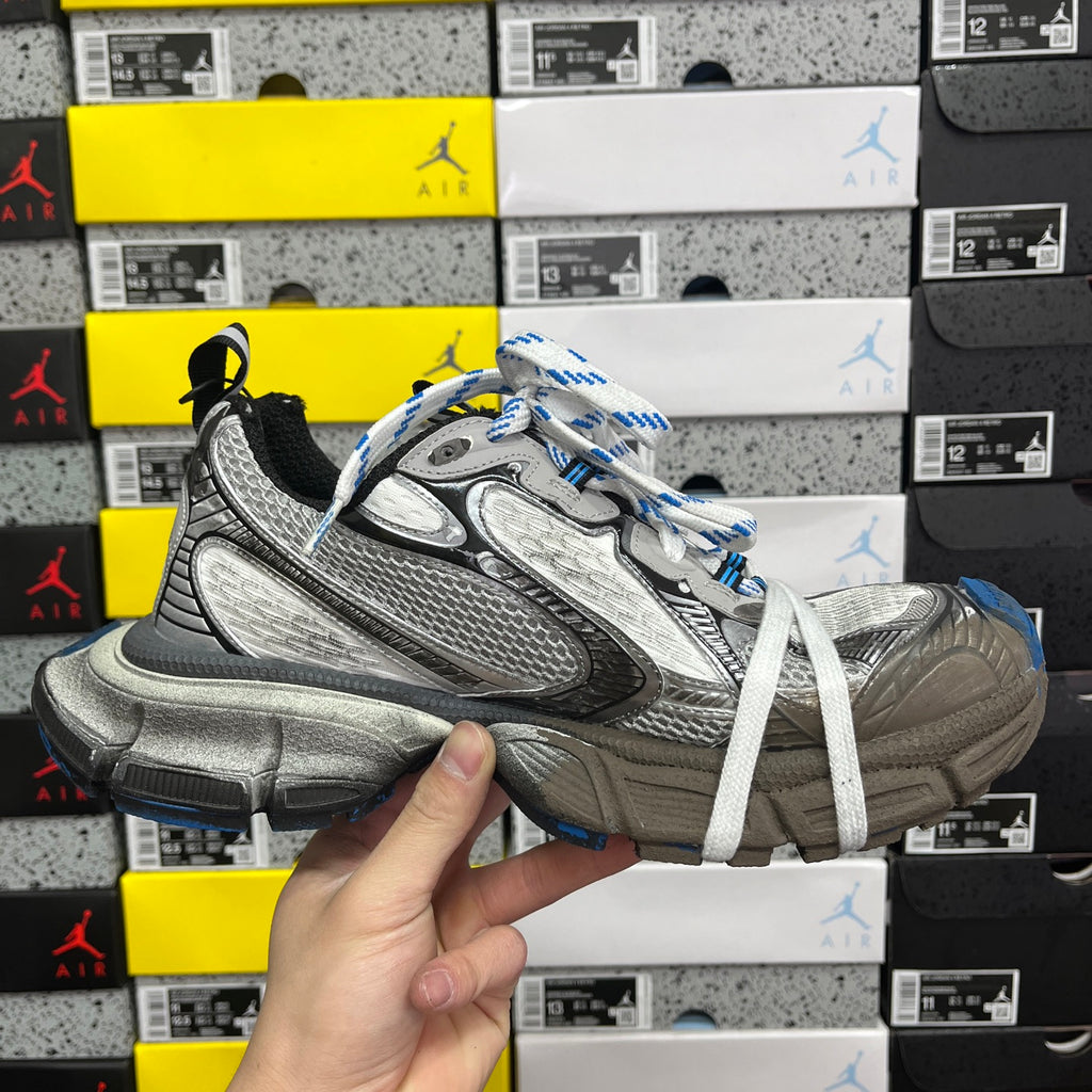 Balenciaga unisex silver sneakers, three-quarter view with black trim and blue-striped white laces