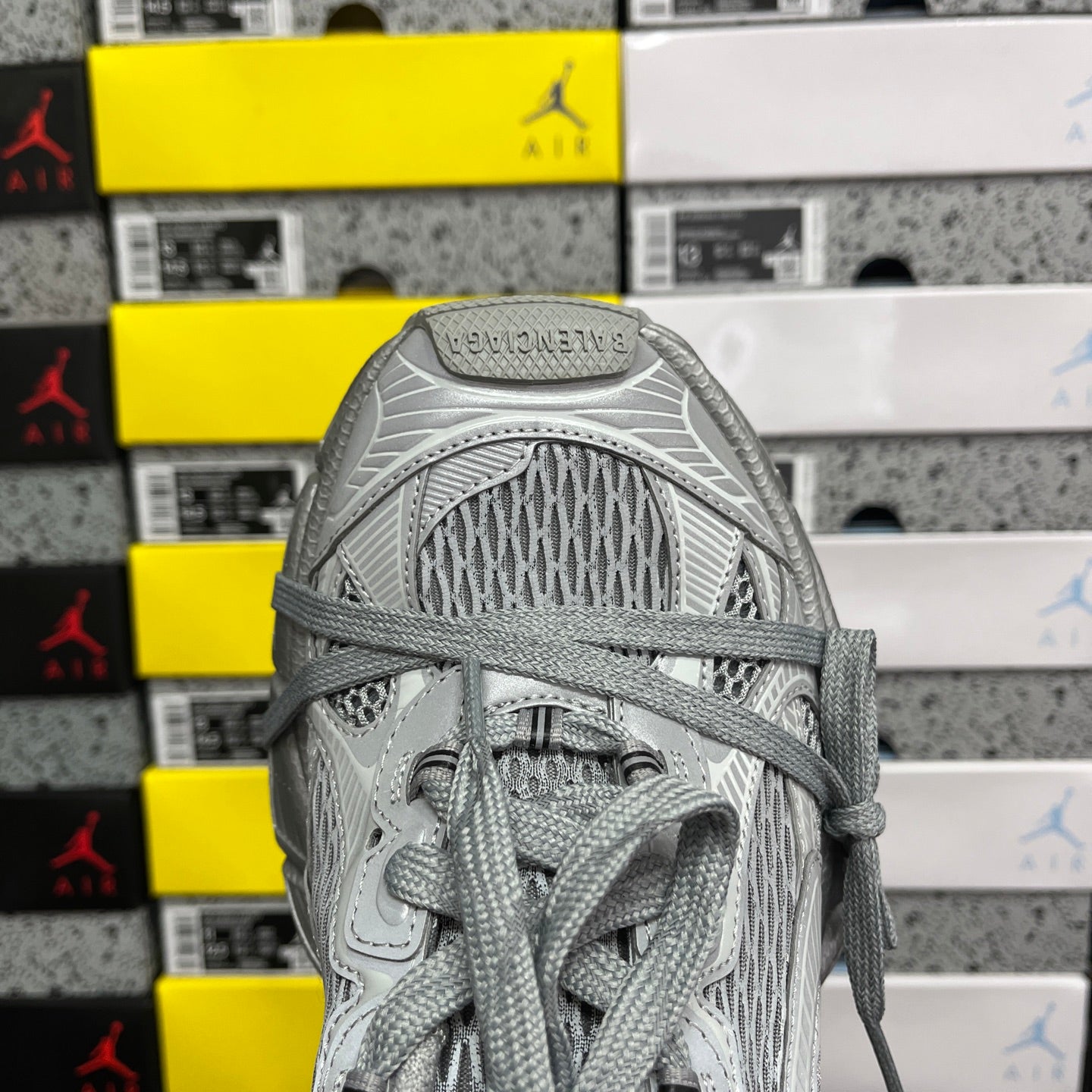 Gray mesh sneaker upper with lace loops and woven textile at the heel