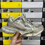 Silver-gray lace-up running sneaker with textured panels and cushioned sole.