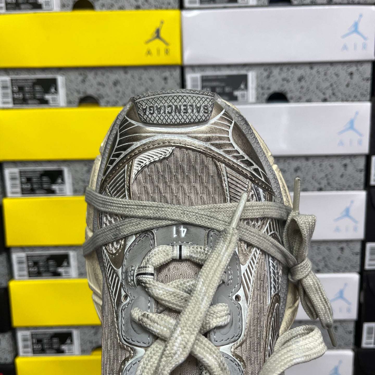 Silver-gray lace-up sneaker tongue with logo patch and mesh-textured upper.