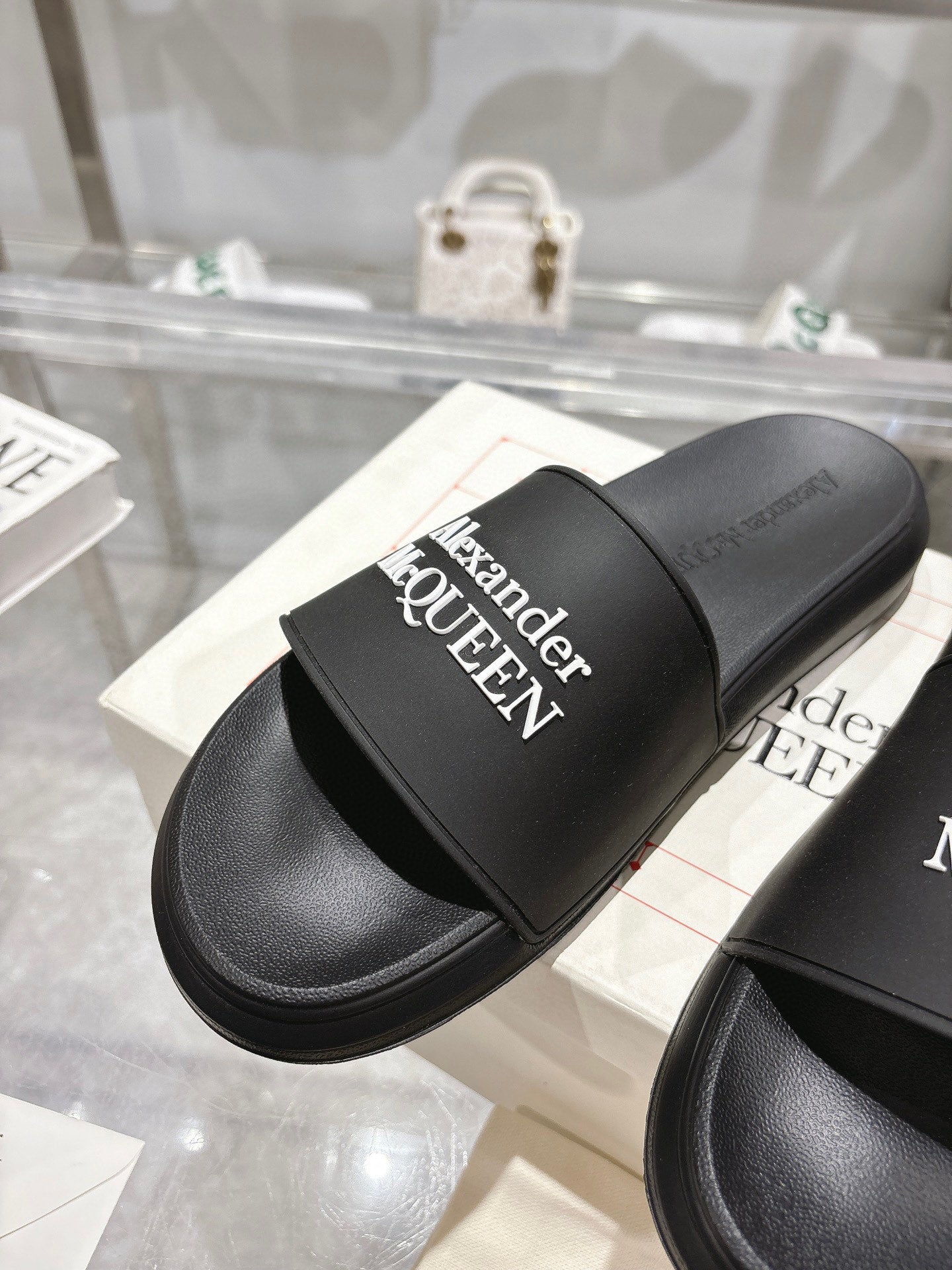 Black Alexander McQUEEN slide sandal with wide strap and logo, close-up