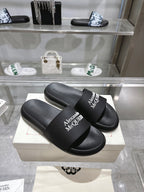 Black Alexander McQUEEN slide sandals with wide logo strap, angled pair