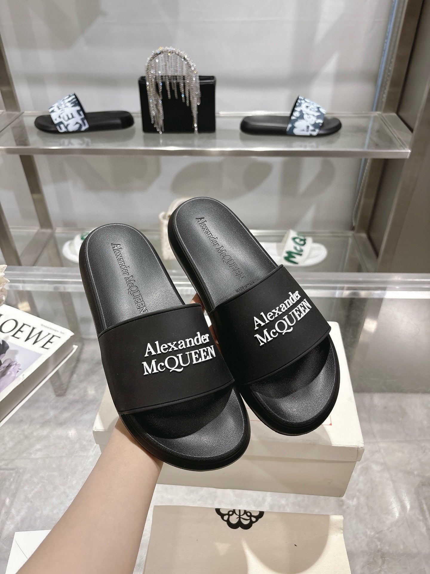 Two black Alexander McQUEEN slide sandals with wide logo strap, shown close