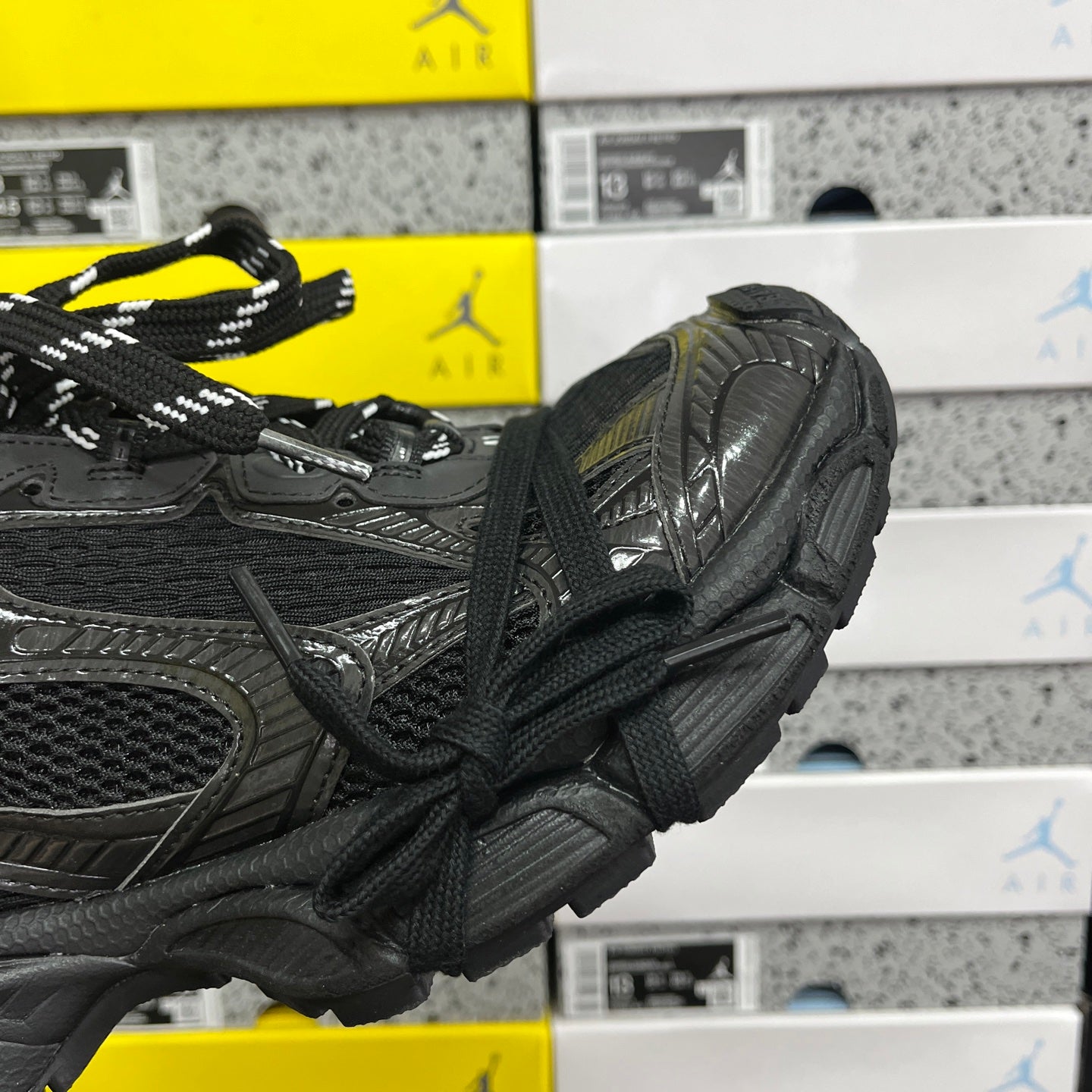 Black Balenciaga sneaker side profile with laces, straps, and embossed textures