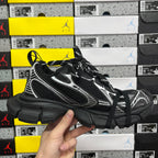 Black athletic sneaker front quarter view with white side stripes and black laces