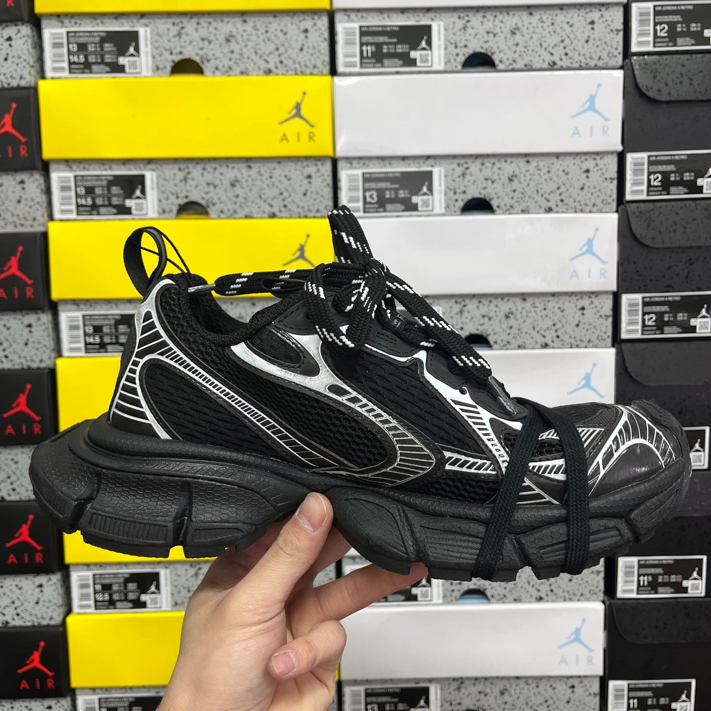 Black athletic sneaker front quarter view with white side stripes and black laces