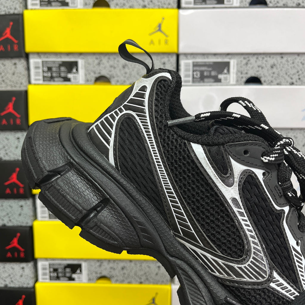 Black sneaker quarter view with white panel detailing and black lace-up upper