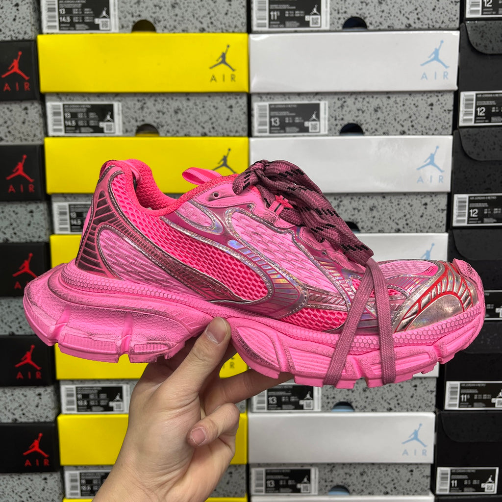 Pink lace-up sneakers held in hand, side logo panel and chunky sole