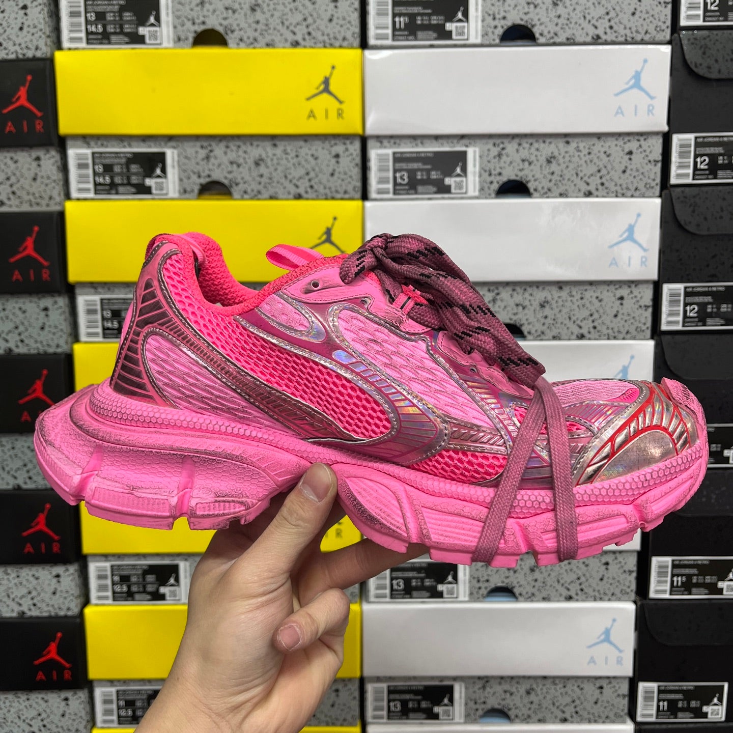 Pink lace-up sneakers held in hand, side logo panel and chunky sole