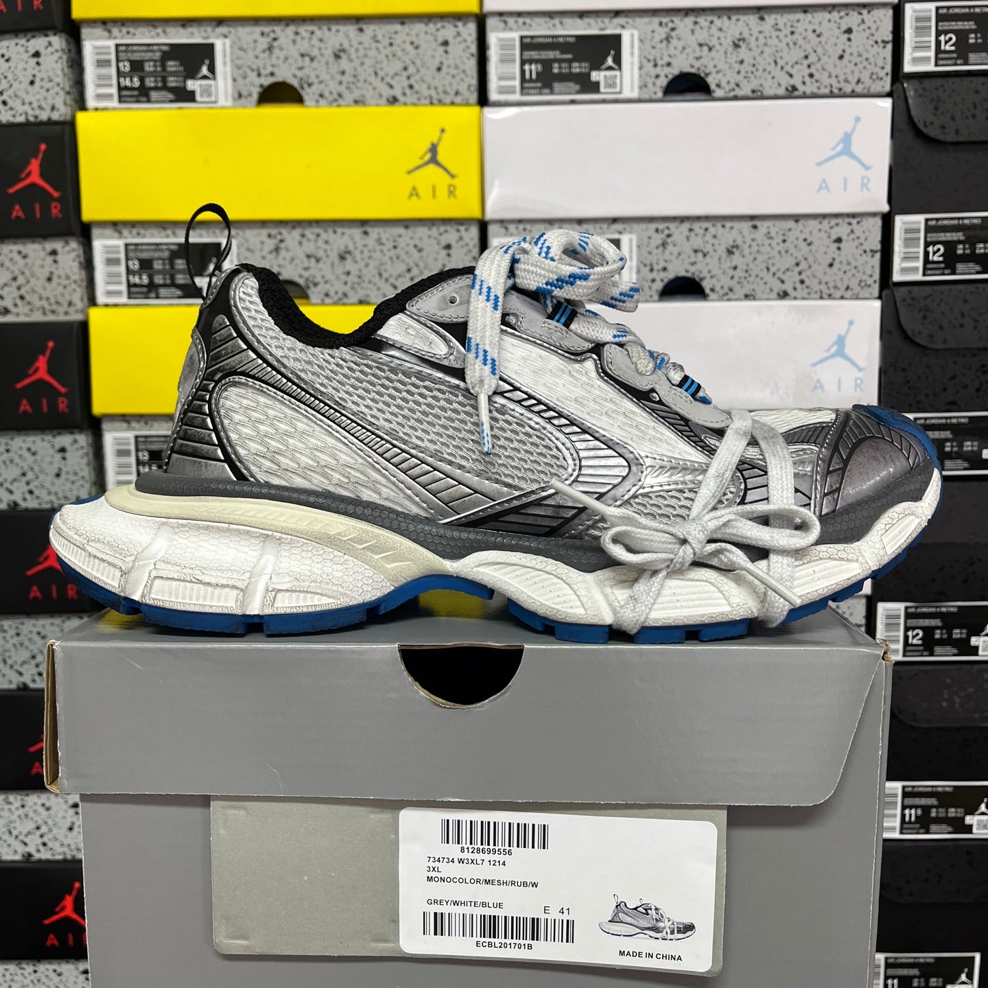 Gray and black lace-up sneaker with white laces, blue detailing, and chunky sole