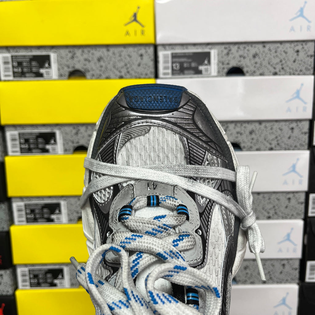 Gray and black sneaker toe view with blue-striped laces and textured mesh panels