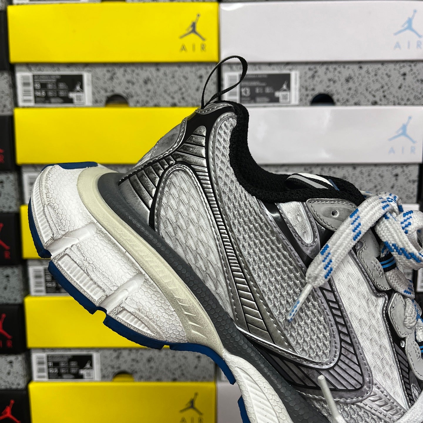 Black and gray lace-up sneaker with white laces, blue-and-white lace trim