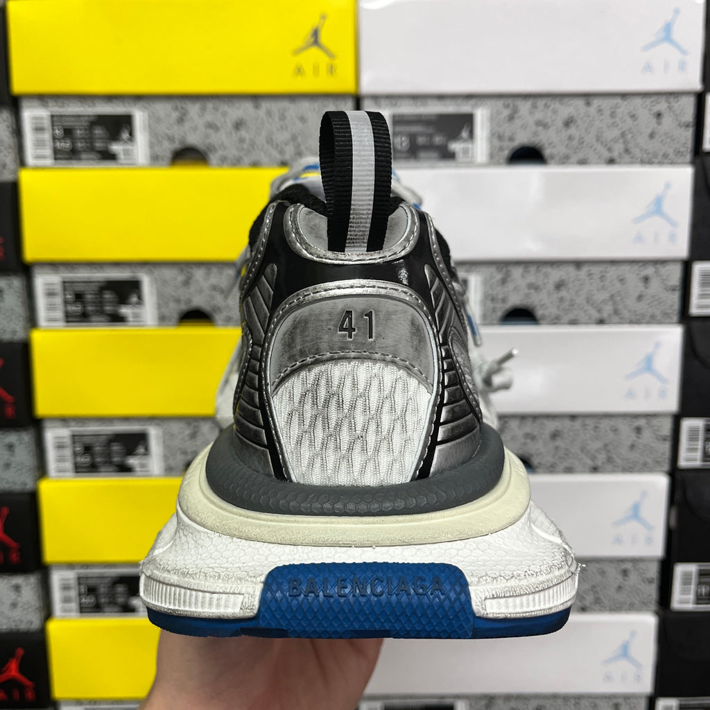 Rear view of gray sneaker with black heel pull tab and blue outsole edge