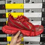 Red lace-up athletic sneaker with gold-toned stripes and chunky treaded sole