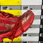 Red sneaker side view with gold-toned overlays and thick running sole