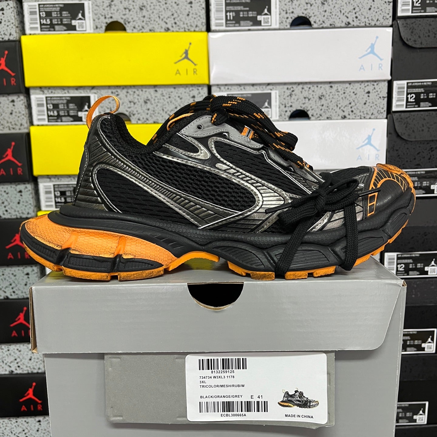 Black and silver lace-up sneaker with orange outsole and textured side panels