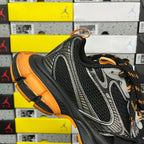 Black and silver sneaker with orange heel accent and lace-up closure