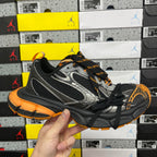 Black, silver and orange low-top sneaker with mesh panels and lace-up closure