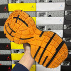 Orange treaded sneaker outsole with black side stripes and rubber lugs